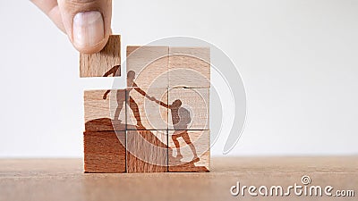 Wooden puzzle of climbers helping each other to reach the summit- concept of teamwork Stock Photo