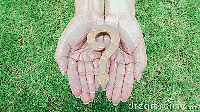 Wooden question marsk on woman hands over green grass background. Ploblem solving concept Stock Photo