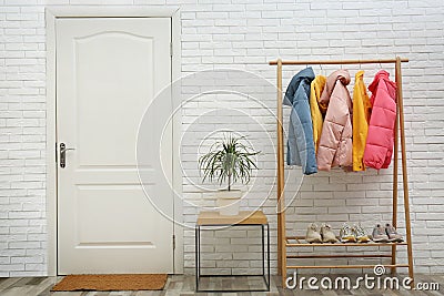 Wooden rack with warm jackets in hallway Stock Photo