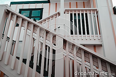 wooden railing with nice vintage white bars going up to cozy house with dark square window in lonely quiet village, west Stock Photo