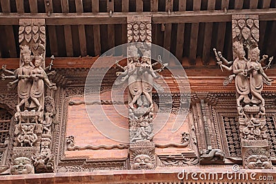 Wooden reapers with elegant carvings of god and and goddess placed in an angles to support the slopped roof of the building in Stock Photo