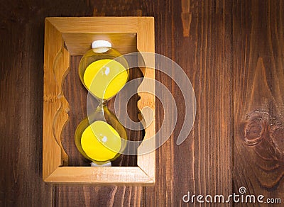 Wooden retro sand glass clock lie on side with sand on wooden background. time stop concept. Stock Photo