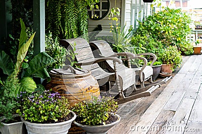 Wooden rocking chairs in a cottage garden porch setting on wooden floor in vintage Thai botanical garden, with traditional Thai ol Stock Photo
