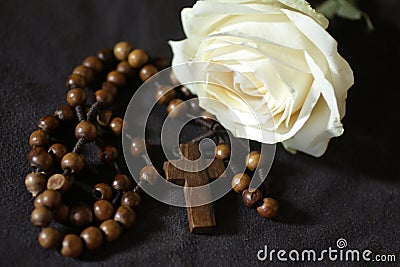 Wooden rosary with Jesus Christ holy cross crucifix and white rose on black background. Catholic rosary symbil Stock Photo