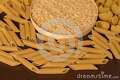 wooden round cup in the middle of italian pasta pepe rigate, snails and penne, Stock Photo