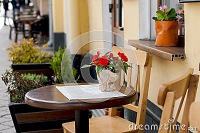 Wooden round table with a flower on the table near cafe. Stock Photo