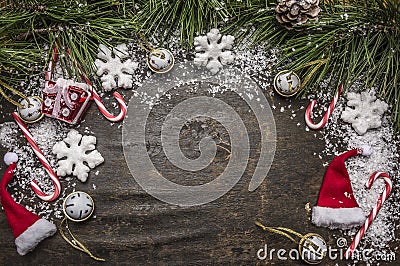 Wooden rustic Christmas snowy background with candy, hat, decorations and green pine branches and cone top view Stock Photo