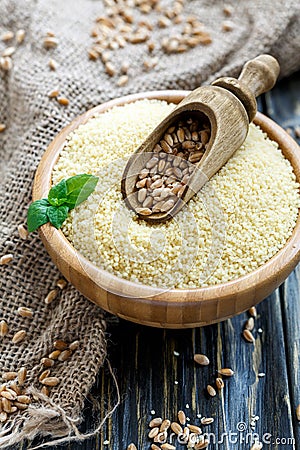 Wooden scoop with wheat in a bowl with couscous. Stock Photo