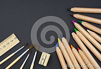 Wooden set of colored pencils, sharpener, brushes and ruler on black background Stock Photo