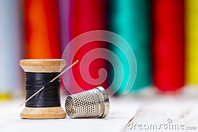 Wooden sewing spool with black thread and metal thimble Stock Photo