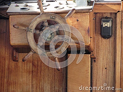 Wooden ship deck with helm and navigation instruments . Particular view of a retro steering wheel of an old sailing vessel Stock Photo