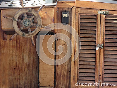 Wooden ship deck with helm and navigation instruments . Particular view of a retro steering wheel of an old sailing vessel Stock Photo