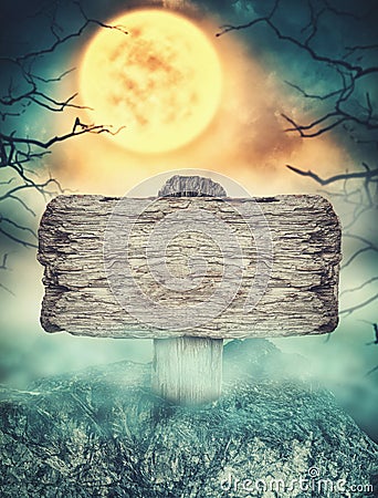 Wooden sign in dark landscape with spooky moon. Halloween design Stock Photo