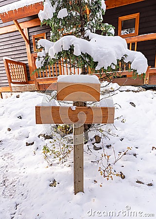 Wooden signboard post with snow covered or guidepost on front of wooden house Stock Photo