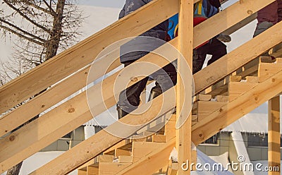 Wooden slide for children in winter, children with sledges and tubing climb the hill, fun at Christmas Stock Photo