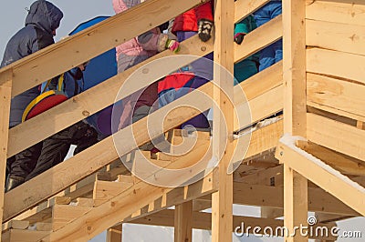 Wooden slide for children in winter, children with sledges and tubing climb the hill, fun at Christmas Editorial Stock Photo