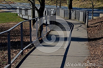 Wooden smooth surface of the ramp for wheelchairs, cyclists and mothers with prams. wooden planks and metal lattice fill the raili Stock Photo