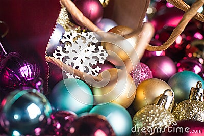 Wooden snow flake in present red bag on multicolour Christmas balls. Sparkling colourful new year tree toys. Holiday Stock Photo