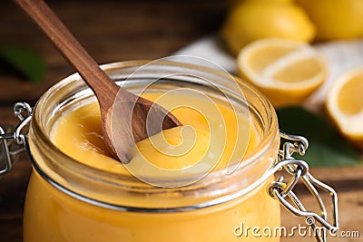 Wooden spoon in jar with lemon curd on table, closeup Stock Photo