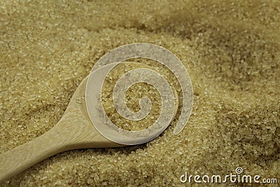 Wooden spoon on pile brown cane sugar texture background. Stock Photo