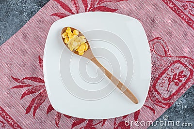 A wooden spoon of popcorn seeds on an empty plate Editorial Stock Photo