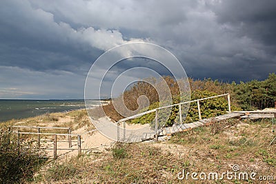 Wooden Stairs In Dunes And Forest Near The Baltic Sea Sand Beach / Scary frightening storm clouds Stock Photo