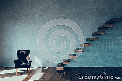 Wooden steps against the gray wall and a black armchair against the gray wall of the plaster. Stock Photo