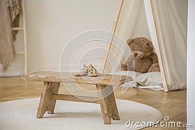 Wooden stool with shoes on white round rug in kid`s room interior with plush toy in tent Stock Photo