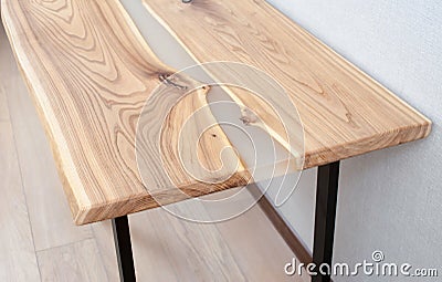 Wooden stylish table made of solid wood with epoxy resin on the background of the floor and wall. Close-up Stock Photo