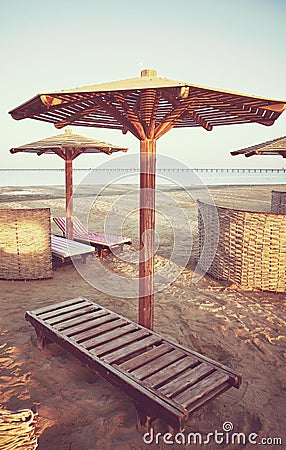 Wooden sun umbrellas, sunbeds and windscreens on beach, color toning applied, Marsa Alam, Egypt Stock Photo