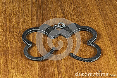 On the wooden surface are metal handcuffs Stock Photo