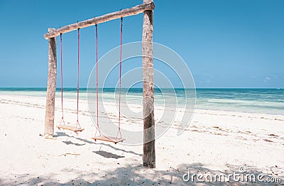 Wooden swing on the beach. Swing with two seats on scenic seascape. Idyllic exotic resort. Tropical paradise. Empty swing. Stock Photo