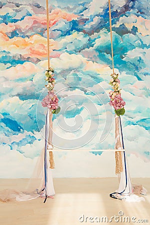 Wooden swing decorated with bouquets of flowers Stock Photo