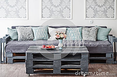 Wooden table with apples on it and glasses of champagne against couch in white room Stock Photo