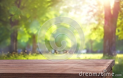 wooden table and blurred natural background with tree branches and grass Stock Photo