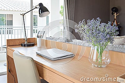 Wooden table with computer notebook,pencil,lamp and flowers in modern working area Stock Photo