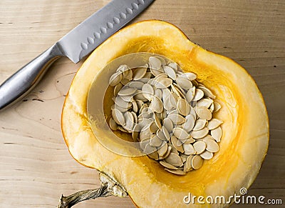 Pumpkin with seeds in bowl on wooden table Stock Photo