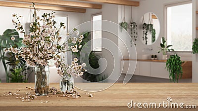 Wooden table, desk or shelf close up with branches of cherry blossoms in glass vase over blurred view of modern bathroom with Stock Photo