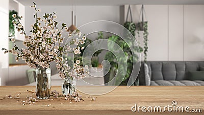 Wooden table, desk or shelf close up with branches of cherry blossoms in glass vase over blurred view of modern kitchen and living Stock Photo