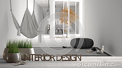 Wooden table, desk or shelf with potted grass plant, house keys and 3D letters making the words interior design, over blurred mini Stock Photo