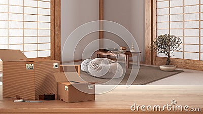 Wooden table, desk or shelf with stack of cardboard boxes over blurred view of meditation room with capet and pillows, modern Stock Photo