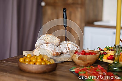 On wooden table is food, vegetables and bread are beautifully laid out, knife sticks out of bread Stock Photo