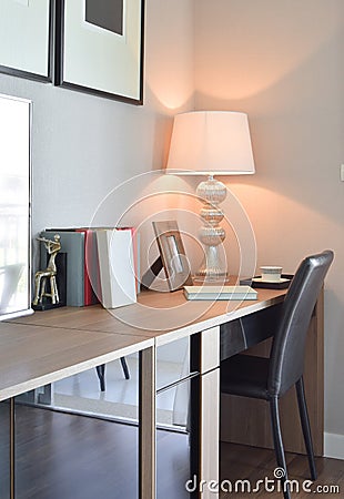 Wooden table with lamp and books in modern working room interior Stock Photo