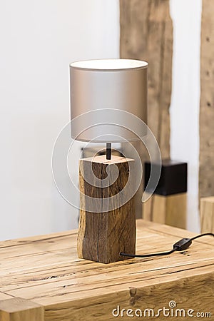 Wooden table lamp made of a piece of wood spruce, a natural original lamp. Glowing bulb wooden table lamp in the interior Stock Photo