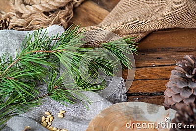 On a wooden table lie coarse gray fabrics, on top of a green pine branch with long needles, a handful of peeled pine Stock Photo