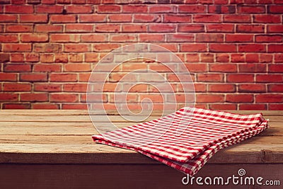 Wooden table with red checked tablecloth over brick wall Stock Photo