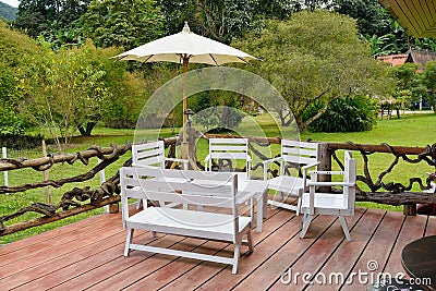 Wooden tables, white chairs in the garden Stock Photo