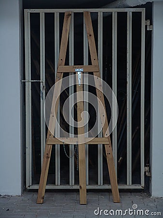 Wooden tall easel standing against a metal garage door in white Stock Photo