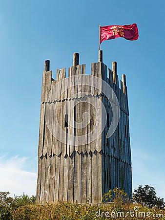 Wooden tower of viking village with viking flag waving against clear blue sky Stock Photo