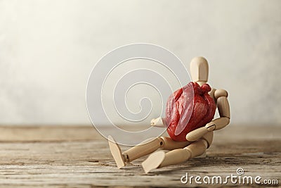 Wooden toy man holds a heart. Donor and transplant, symptoms of an attack. Surgical Assistance Stock Photo